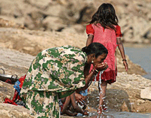 İki Güneydoğu Asyalı kadın nehirde ellerini yıkıyor.