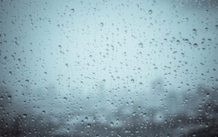 Mevsimsel duygudurum bozukluğu (SAD) hakkında bir SSS göstermek için kasvetli bir günde bir pencereye yağmur damlaları