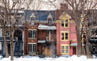 Montreal sıra evleri kışın önden bakıldığında, kar yağıyor ve çıplak ağaçlarla