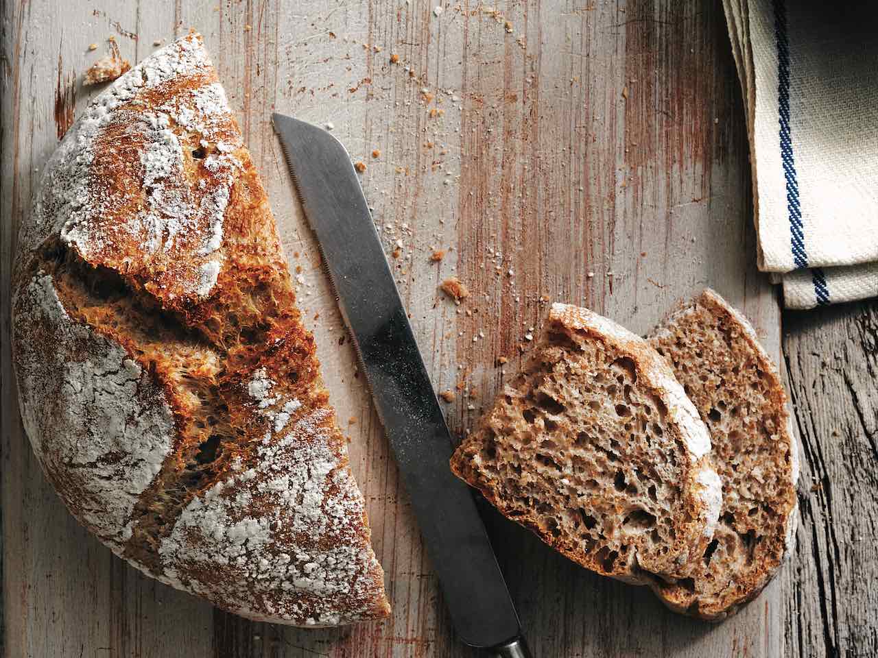 Ahşap bir kesme tahtası üzerinde dilimlenmiş taze un kahverengi ekmek somun
