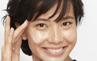 Cilt bakımı maddesi olarak peptitlerle ilgili bir makale için yüz kremi uygulayan bir kadın.