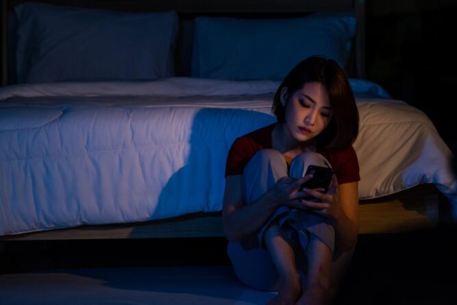 Asyalı kadının yerde oturup telefonuna baktığı gece sahnesi